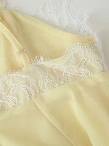 Detail of light yellow chiffon dress featuring white eyelash lace trim and adjustable strap