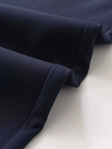 Macro detail of dark blue fabric texture and clean stitching on the straight leg trousers