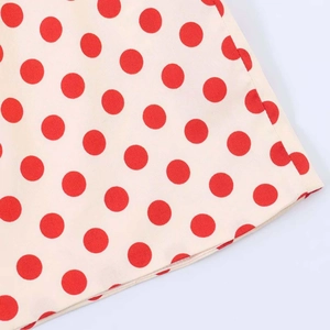 Detail of retro cream fabric with large red polka dots showing smooth weave texture