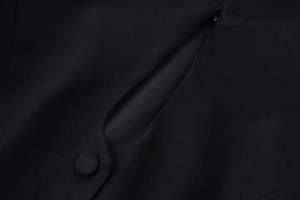 Detail view of the black short sleeve blazer with a teardrop cutout and fabric button