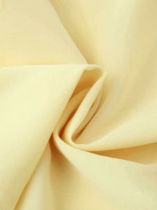 Close-up of light yellow silky textile fabric with elegant lace stitching and soft draping