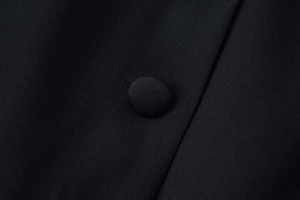 Close-up detail of a premium black blazer featuring a fabric-covered button and woven texture