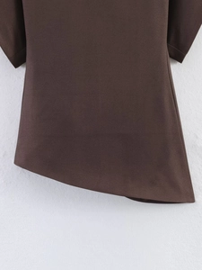 Detail of dark brown garment featuring an asymmetric hem and fine textured fabric