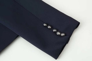 Close-up of premium navy woven fabric with five decorative silver buttons on the cuff