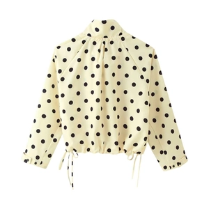 Detailed view of polka dot top featuring high neck collar and adjustable drawstring hem