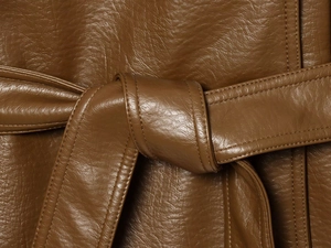 Détail de la veste en similicuir marron avec ceinture nouée et texture grainée