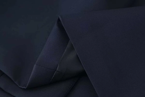 Detailed macro shot of premium navy blue fabric with black silk lining and precise stitching