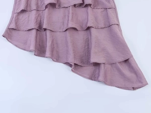 Detail von mehrlagigen asymmetrischen Rüschen an einer malvenfarbenen Plissee-Bluse