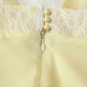 Pale yellow summer dress featuring white lace patchwork and matching fabric-covered buttons