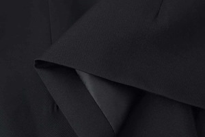 Close-up of black blazer fabric showing woven texture and smooth satin lining finish