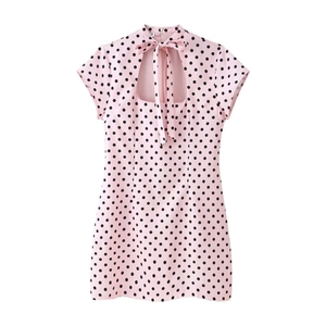 Détail de robe courte rose à pois avec nœud au col et étiquette de taille M