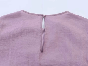 Detail der hellvioletten Rüschenbluse mit Rundhalsausschnitt und Knopfverschluss hinten