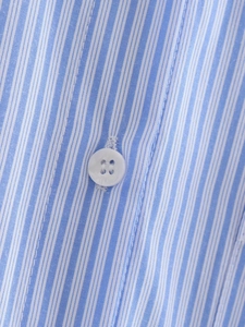 Macro detail of blue and white striped cotton shirt with a white four-hole resin button