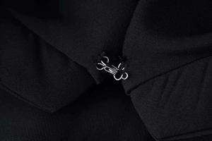 Macro detail of silver metal hook-and-eye closure on black slim-fit blazer waist