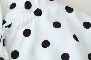 Detailed close-up of retro white polka dot fabric with drawstring and black buttons