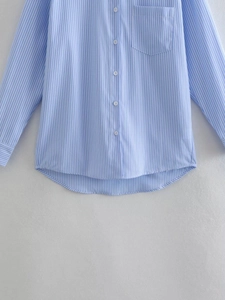 Detail of blue striped shirt showing button placket, chest pocket and fabric texture