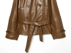 Détails de la veste en similicuir marron avec double boutonnage et ceinture à la taille