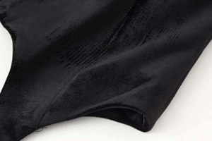Dettaglio della texture in velluto nero con strisce verticali di un blazer a collo alto