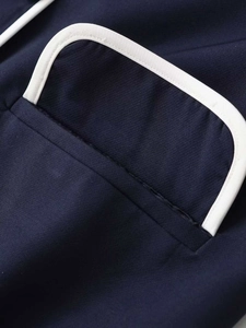 Detail of navy blue cardigan pocket with contrast white piping and fine plain weave texture