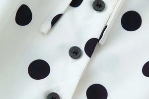 Detailed close-up of black buttons and polka dot pattern on white woven fabric