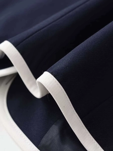 Macro detail of dark blue fabric with white contrast piping and high-quality twill texture