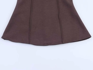 Détail du tissu côtelé marron foncé avec coutures verticales et ourlet inférieur arrondi