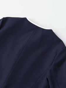 Detail view of navy blue blazer neckline featuring premium white contrast piping decoration
