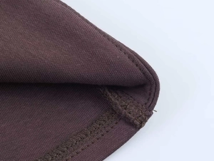 Détail du tissu en maille marron foncé avec coutures surjetées précises sur le bord