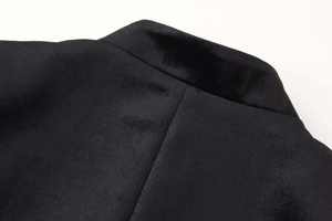 Dettaglio ravvicinato di un blazer in velluto nero con collo alto e texture raffinata