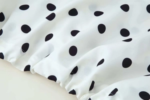 Detailed macro view of the white fabric with black polka dots and elastic drawstring hem