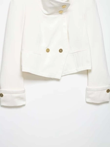 Detail of white cropped blazer with stand collar and decorative embossed gold buttons
