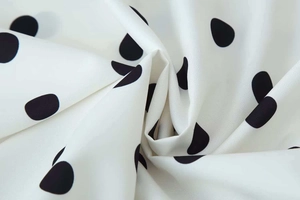 Close-up of lightweight chiffon fabric with black polka dots and smooth texture details