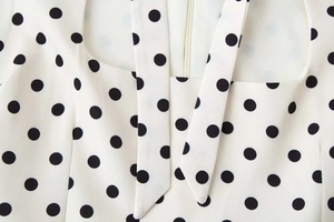 Gros plan du décolleté carré avec imprimé à pois et détail de lien noué sur la robe