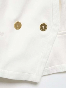Detailed close-up of white cropped blazer fabric and premium gold metallic buttons