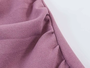 Macro shot of dark mauve textured crepe fabric showing soft drape and refined seam detail