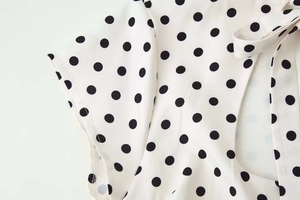 Détail du tissu à pois blancs avec design à nouer et coutures sur le décolleté
