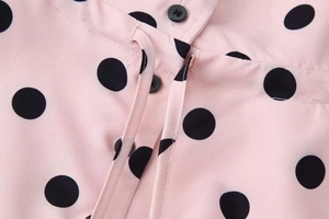 Close-up of pink polka dot shirt with black buttons and high-quality fabric texture
