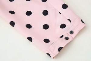 Detailed view of pink polka dot blouse cuffs featuring two black round buttons