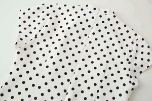 Détail d'une robe blanche à pois avec fermeture éclair invisible et col montant chic