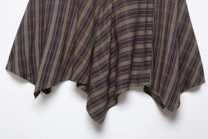 Macro shot of brown plaid skirt featuring an asymmetric hem and vertical stripe pattern