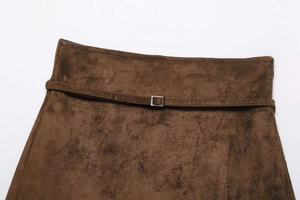Detailed close-up of brown suede mini skirt fabric texture and silver buckle waist belt