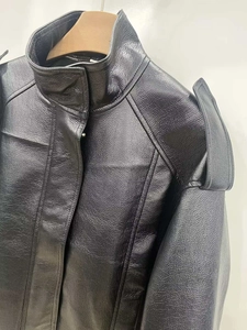 Detail of black faux leather bomber jacket showing stand collar and epaulet texture
