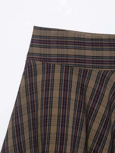 Macro detail of high-quality brown plaid woven fabric and waist tailoring on the skirt