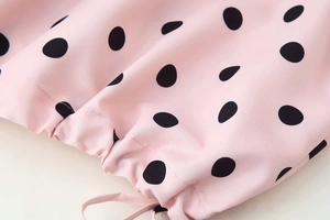 Detail of pink polka dot fabric with adjustable drawstring hem and soft pleats
