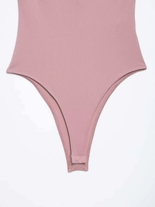 Detail view of dusty pink bodysuit featuring snap button closure and seamless knit fabric