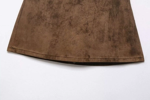Detailed close-up of dark brown faux suede fabric and double-stitched hem texture