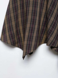 Detail of vintage plaid skirt showing asymmetrical hem and woven texture in brown and blue