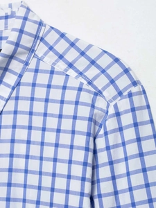 Détails des coutures aux épaules et du col d'une chemise à carreaux bleu et blanc