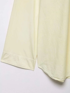 Detail view of light yellow cotton poplin shirt showing wide cuffs and rounded hemline