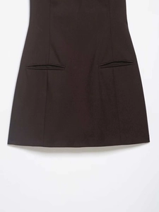 Close-up of brown dress featuring symmetrical horizontal pockets and vertical seams